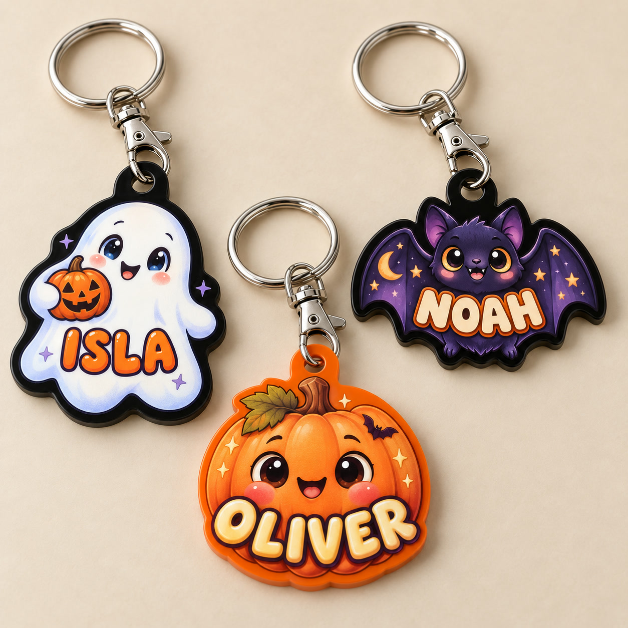 Design preview of personalised Halloween acrylic keyrings: ISLA ghost on black, OLIVER pumpkin on orange and NOAH purple bat on black, each with silver lobster clasp and split ring.
