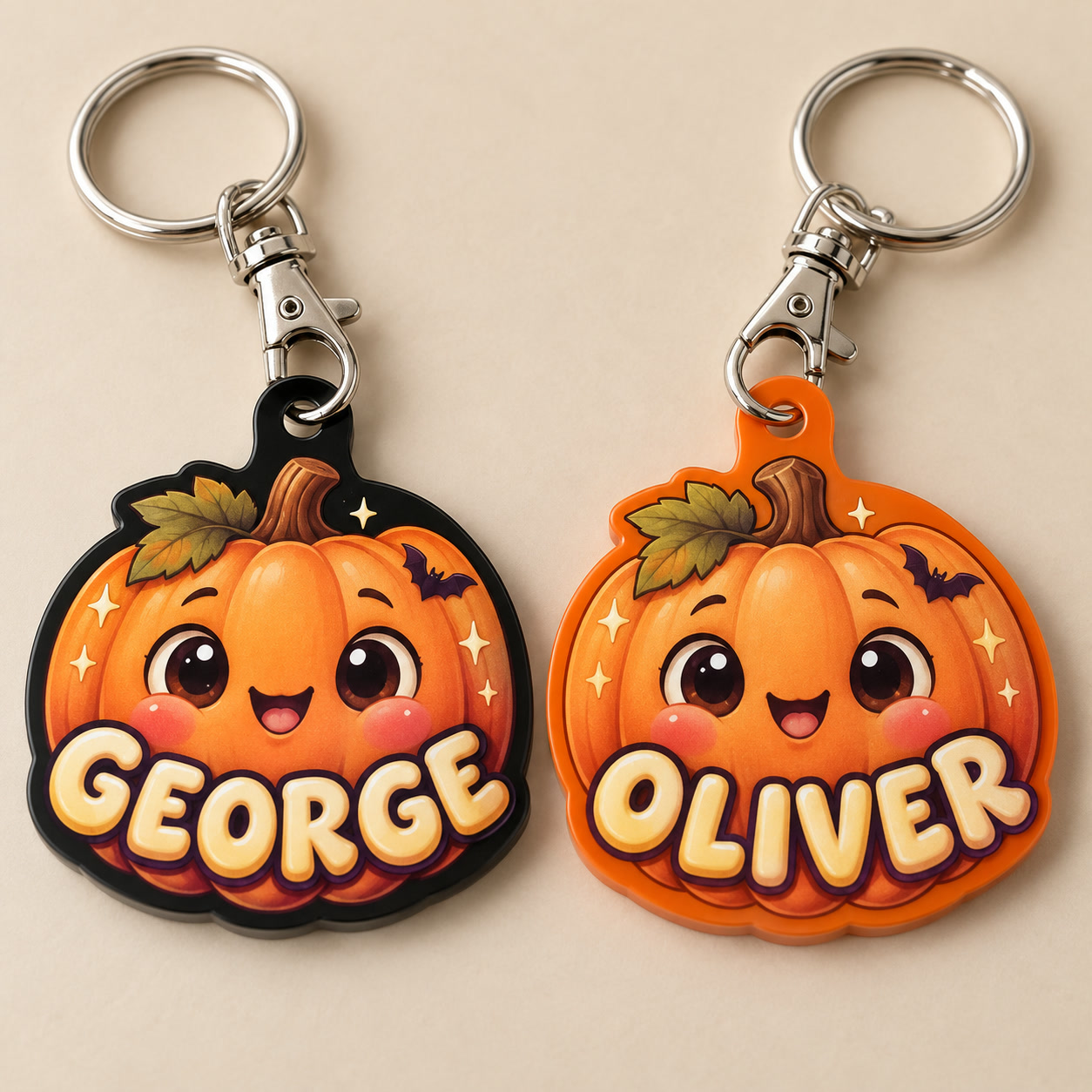 Pumpkin design preview: orange illustrated personalised pumpkin keyrings named GEORGE on black acrylic and OLIVER on orange acrylic, with silver lobster clasps and split rings.