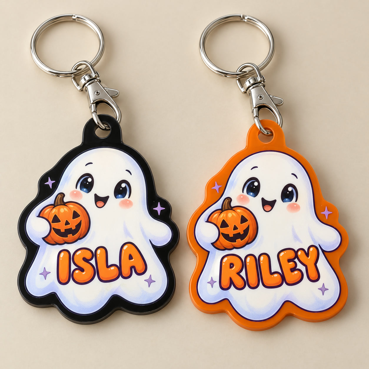 Ghost design preview: white illustrated Halloween ghost charms named ISLA on black acrylic and RILEY on orange acrylic, each holding a printed pumpkin.