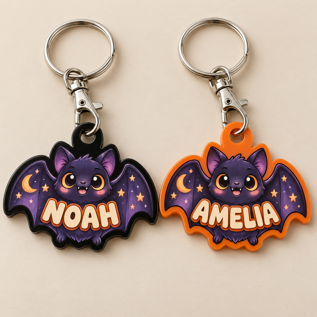 Bat design preview: purple illustrated Halloween bat charms with moon and stars, named NOAH on black acrylic and AMELIA on orange acrylic.